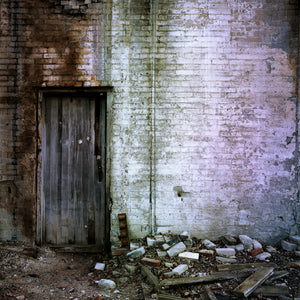 Old wooden doorway surrounded by crumbling brick wall
