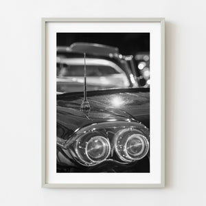 Black and white photograph of vintage car antenna and blurred tail lights