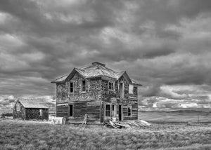weathered wooden farmhouse under dramatic cloud sky Saskatchewan