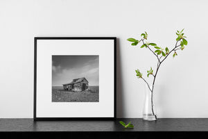 black and white abandoned prairie homestead with dramatic sky