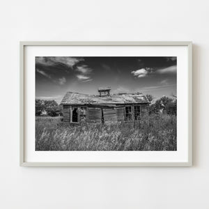 Abandoned Saskatchewan farmhouse collapsing in tall prairie grass black and white