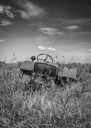 rusted farm tractor partially buried in field Canada monochrome