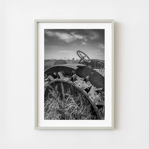 Rusting tractor wheel and steering wheel in tall prairie grass