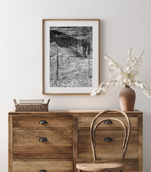 Dark cliff streaks and pale sandstone contrast above irregular wooden fence posts.