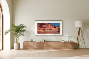 Warm red cliffs stretch across a sunlit desert landscape at Canyon de Chelly.
