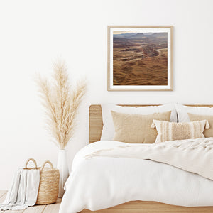 Square photograph of Canyonlands with deep ravines and distant mesa silhouettes.