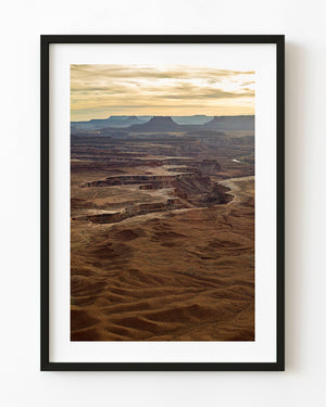 Canyonlands National Park desert landscape with layered cliffs beneath a golden sky.