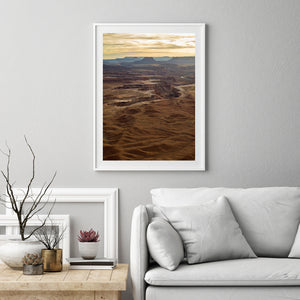 Warm evening light falls across canyon ledges beneath a pale gold sky.