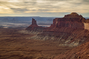 A wide Utah desert landscape with red sandstone towers and a softly glowing evening sky.