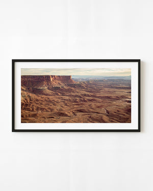 A red mesa rises above rugged desert terrain in Canyonlands National Park, Utah.
