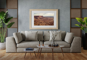 Warm red cliffs contrast with patterned brown ridges across the Canyonlands desert.