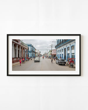Classic cars and pedestrians along a colourful street in Cárdenas, Cuba.