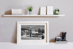Monochrome diner photograph with a classic car, American flag and small town street.