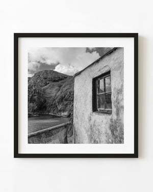 Black and white photograph of the weathered Carrick-a-Rede fishing hut in Northern Ireland.