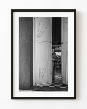 Black and white photograph of a woman standing inside a white doorway in Cartagena, Colombia.