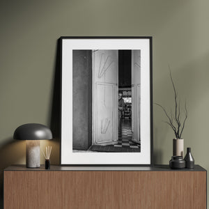 Vertical Colombian street photograph contrasting bright door panels with deep interior shadows.