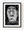 Black and white photograph of an expressive carved wooden face holding a cigar.