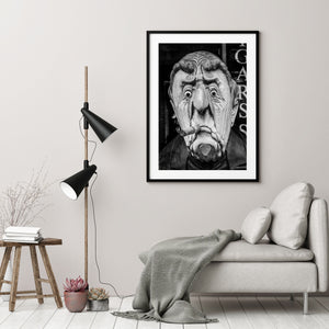 A cigar smoking wooden sculpture captured with fine texture and strong tonal contrast.
