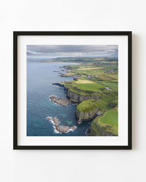 Aerial photograph of Causeway Coast cliffs and green fields beside the sea in Northern Ireland.