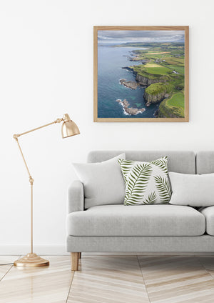 White surf traces the base of dark cliffs along the Northern Ireland shore.