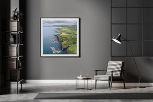 Causeway Coast aerial view showing grassy headlands, coastal cliffs and distant farmland.