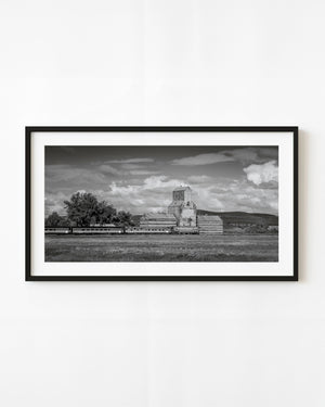 Black and white photograph of a grain elevator and train in Chamberlain, Saskatchewan.