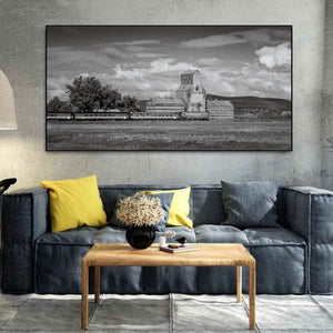 Clouds and open fields surround a historic grain elevator in Chamberlain, Saskatchewan.