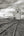Curving rails cross open prairie toward a tall wooden elevator beneath textured clouds.