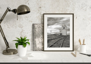 Monochrome Canadian rural photograph with a grain elevator rising above the railway.