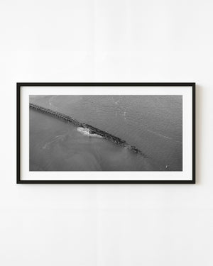 Black and white aerial photograph of a coal-terminal trestle extending across water in Charleston.