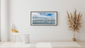 A broad blue sky frames Ravenel Bridge and its reflections across calm water.