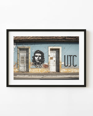 Che Guevara portrait and UJC lettering appear on a weathered blue facade in Cuba.