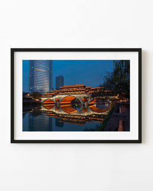 Illuminated Anshun Bridge reflects in calm river water beneath a blue evening sky in Chengdu.