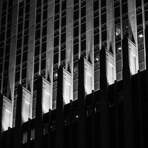 Light catches repeating vertical details along a Chicago building above deep shadows at night.