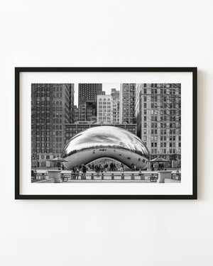 Chicago’s Bean sculpture reflects nearby buildings above visitors in a black and white city photograph.