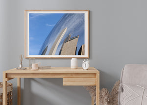 Blue sky and distorted office buildings meet along a curved metallic surface in Chicago.