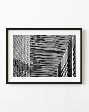 Black and white Chicago architecture photograph with curved balconies between reflective glass facades.