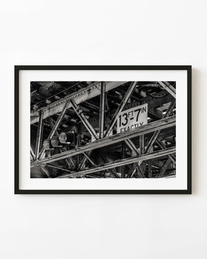 Black and white photograph of intersecting steel beams beneath Chicago’s elevated L train tracks.