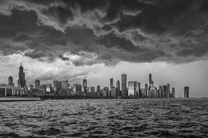 Choppy Lake Michigan water leads toward Chicago towers under a dramatic layered cloud bank.