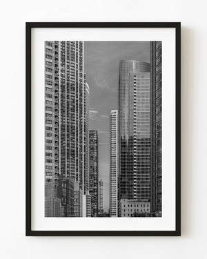 Black and white view through a canyon of Chicago skyscrapers toward a smaller ornate tower.