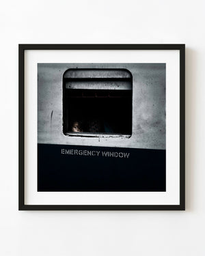 Colour documentary photograph of a child near the edge of a dark emergency window on an Indian train.