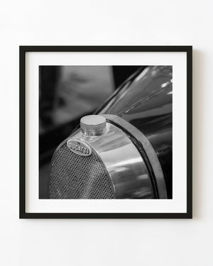 Black and white close-up of a classic Bugatti radiator with its oval badge, mesh grille and polished metal surround.