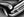 Polished chrome and a circular headlight define a vintage Chevrolet front corner in monochrome.