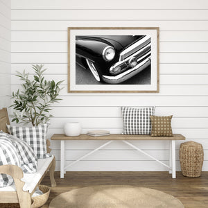 Classic-car detail photograph with a rounded headlight above a bright chrome bumper and grille.