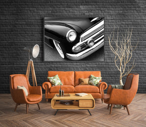 Monochrome automotive photograph showing a vintage car’s headlight, chrome trim and whitewall tyre.
