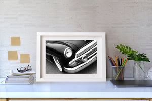 Bright reflections trace the bumper and grille beneath a classic Chevrolet’s dark fender.