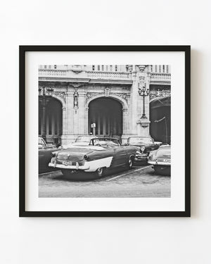 Black and white photograph of classic convertibles parked before an ornate hotel facade in Havana, Cuba.