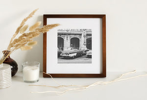 Classic cars form a loose arrangement below the formal facade of a Havana building.