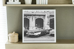 Square Havana photograph showing classic American cars in front of ornate historic architecture.