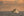 Colour nautical photograph of a vintage yacht on textured water under a peach-gold sky.